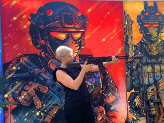 Женщина с автоматом на фоне арт-персонажей LASERWAR.